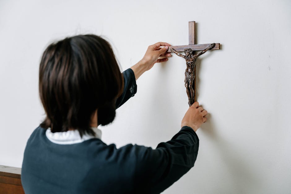 Man hanging crucifix white wall